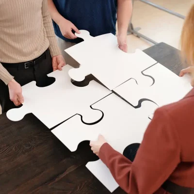 Team of adults working together on large puzzle pieces, symbolizing teamwork and unity.